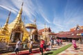 Buddhist people praying and walking around a golden pagoda.